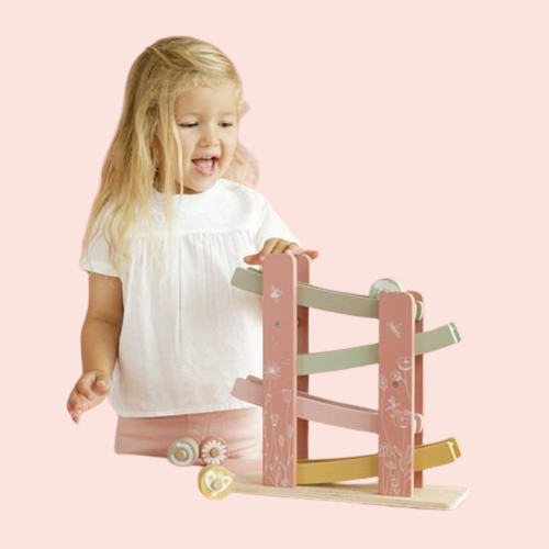 Meitene spēlējas ar koka rampas rotaļlietu rozā toņos