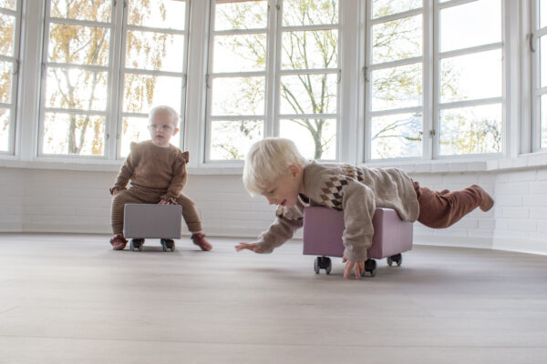 Bērni spēlējas ar mazajiem sērfotājiem gaišā istabā ar lieliem logiem