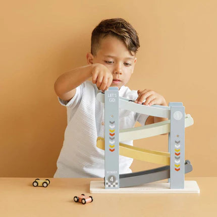 Zēns spēlējas ar Little Dutch koka mašīnu trasi un vairākām koka mašīnītēm.