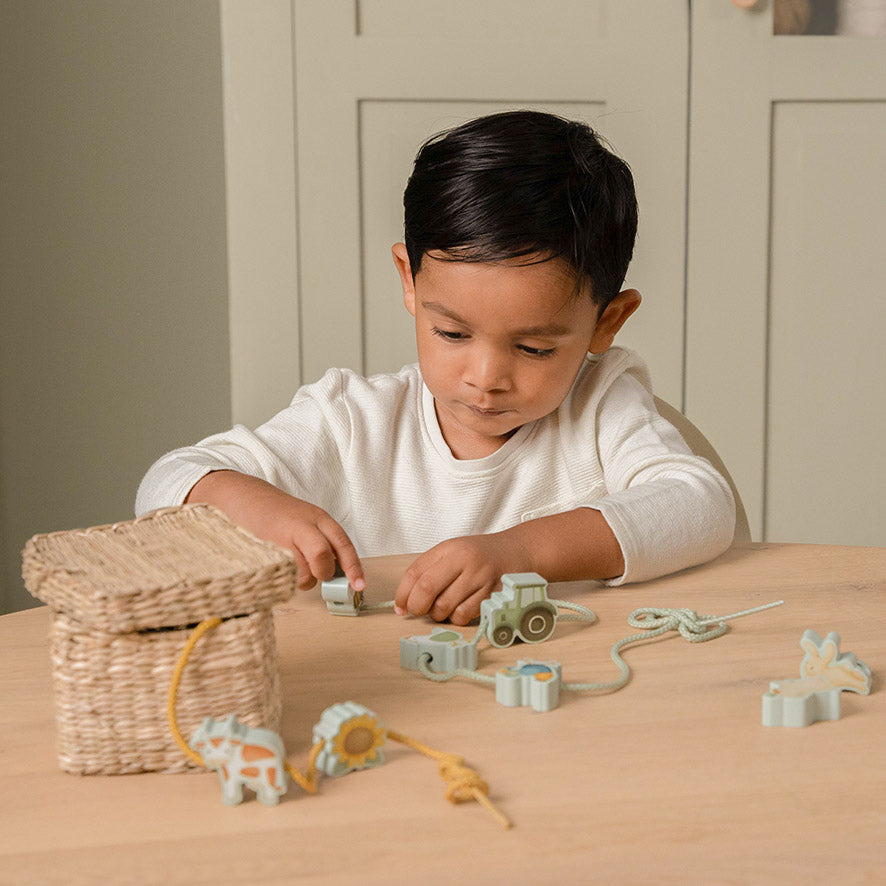 Bērns ver koka krelles, attīstot radošumu un smalko motoriku – radošā rotaļlieta bērniem