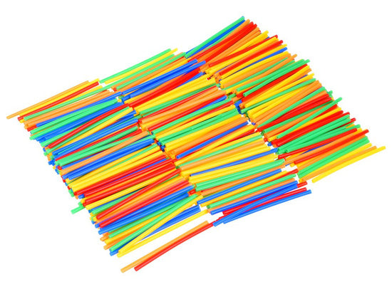 Bērns būvē krāsainu konstrukciju no salmiņu komplekta, attīstot radošumu un iztēli.